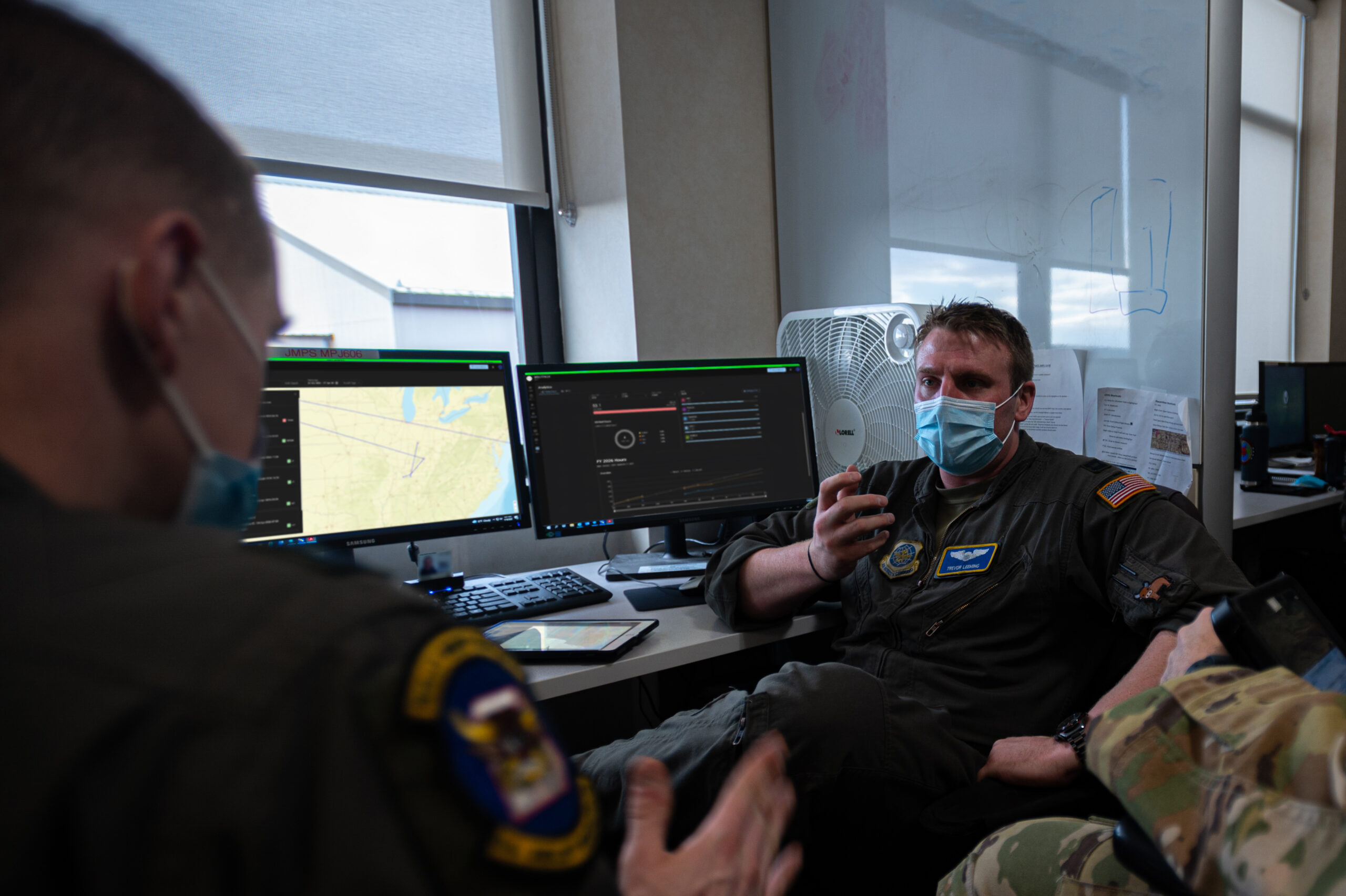 Aircrew members discussing a mission at workstations running WOLFPACK
