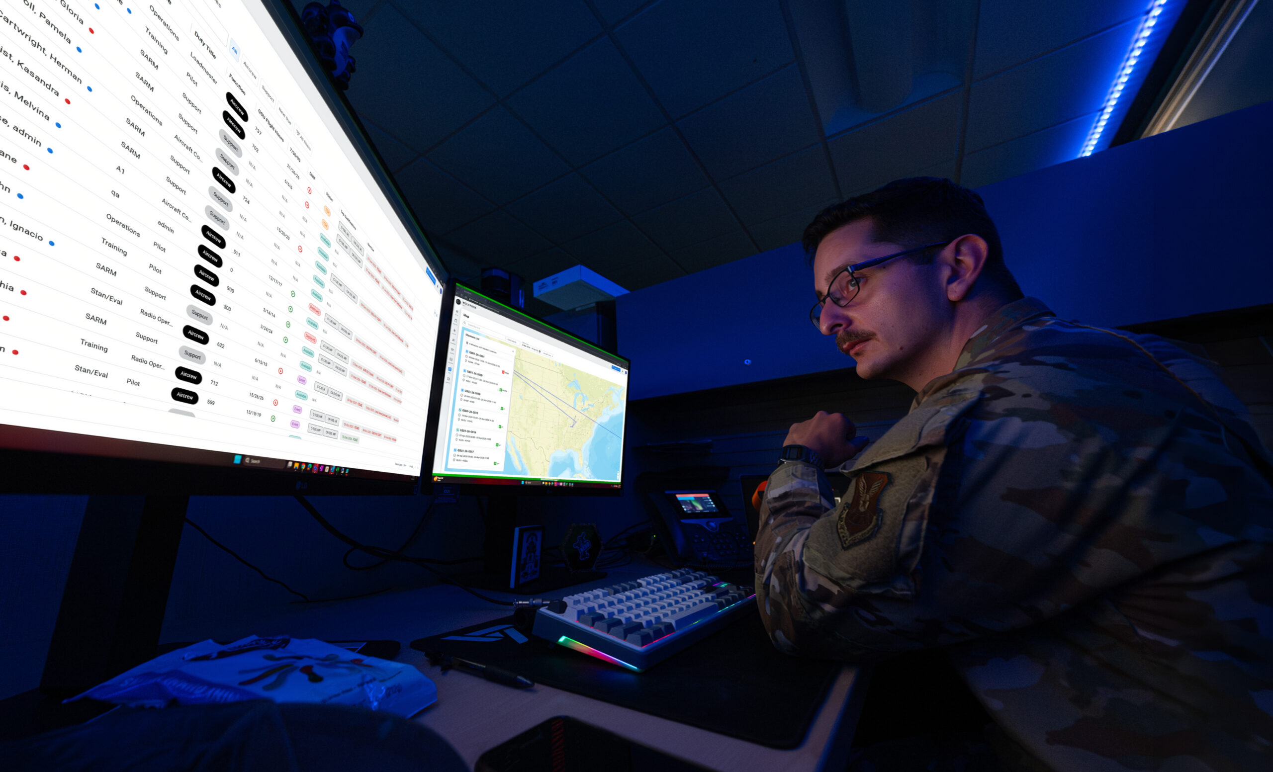 Operator reviewing WOLFPACK aircrew and aircraft status tables on large monitors